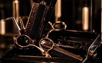 Gold scissors, combs and brushes on a black tray